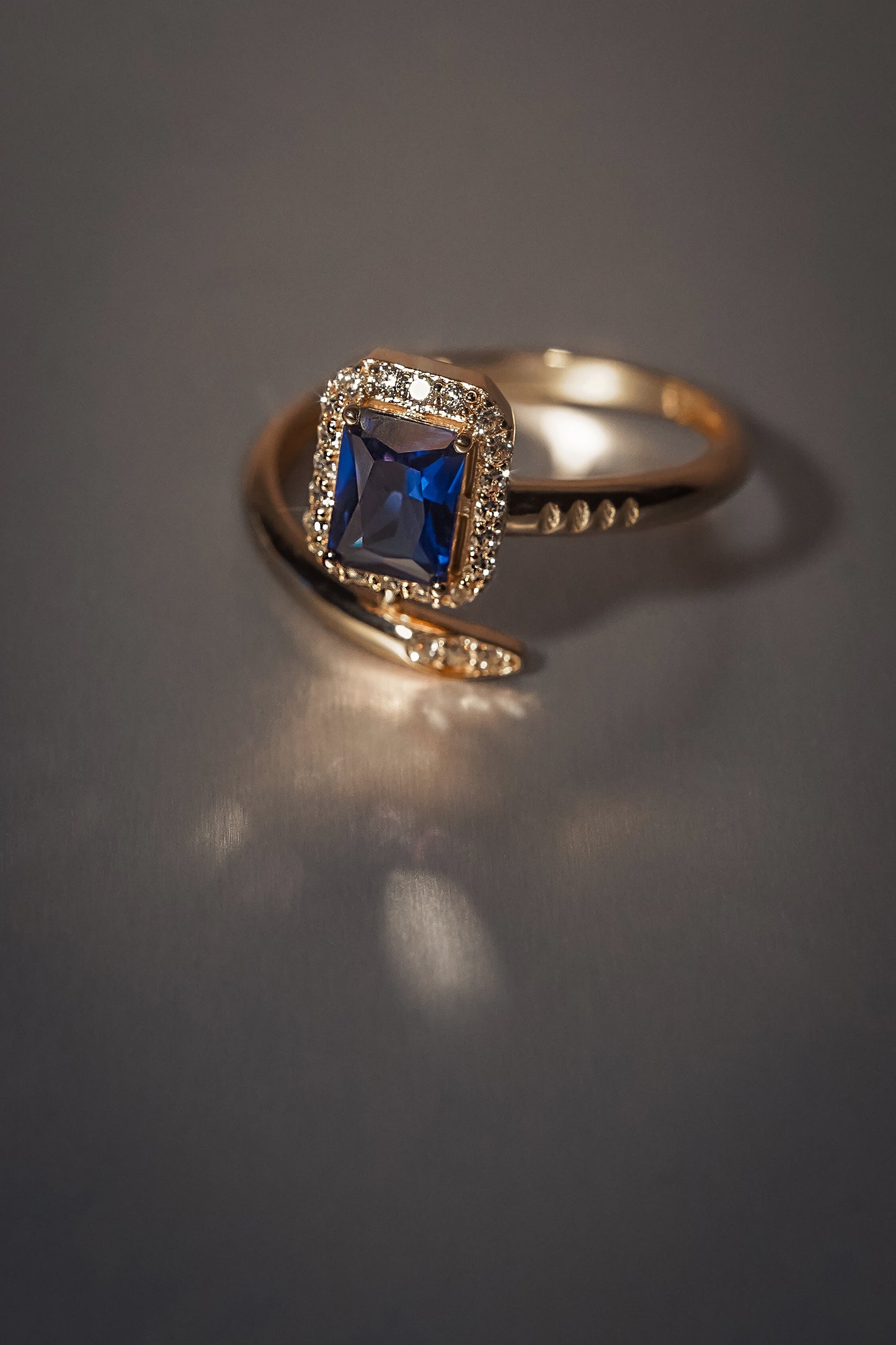 Каблучка з червоного золота з фіанітами. По центру має великий фіаніт голубого кольору на сірому фоні