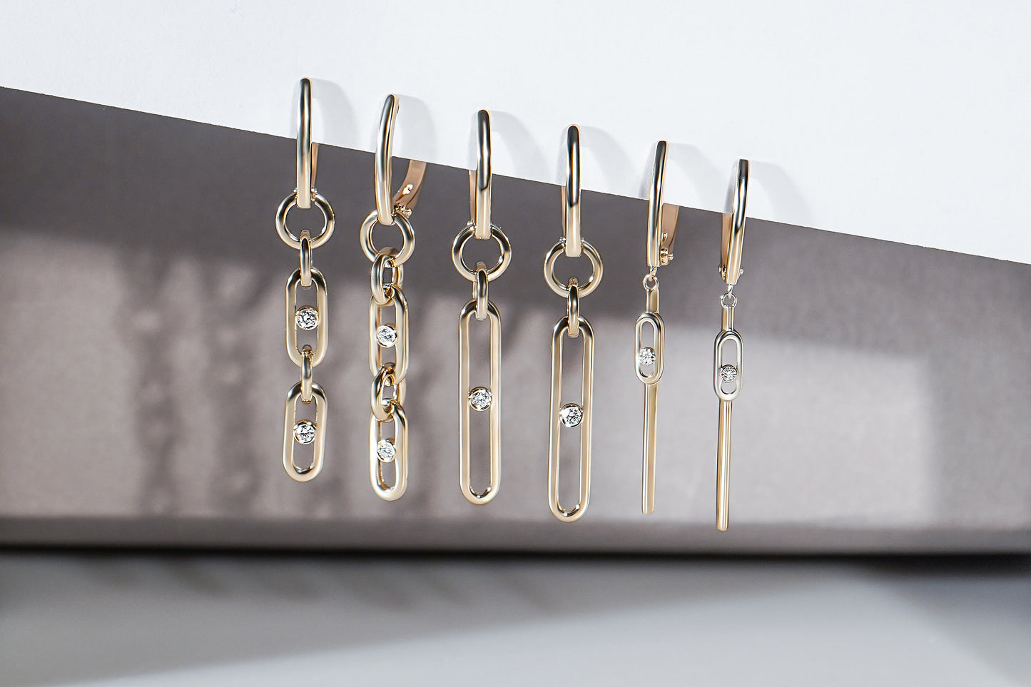 Три пари довгих сережок з діамантами на сіро-білому фоні