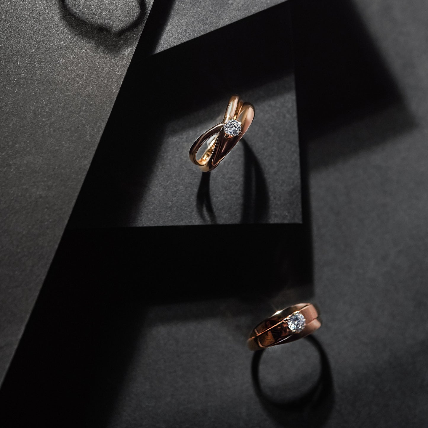 Чотири каблучки з червоного золота зображені на чорних підставках з парепу