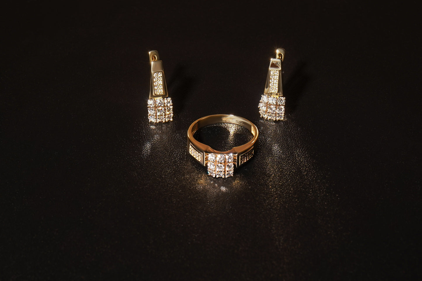 Сережки та каблучка з діамантами з червоного золотана зорному фоні