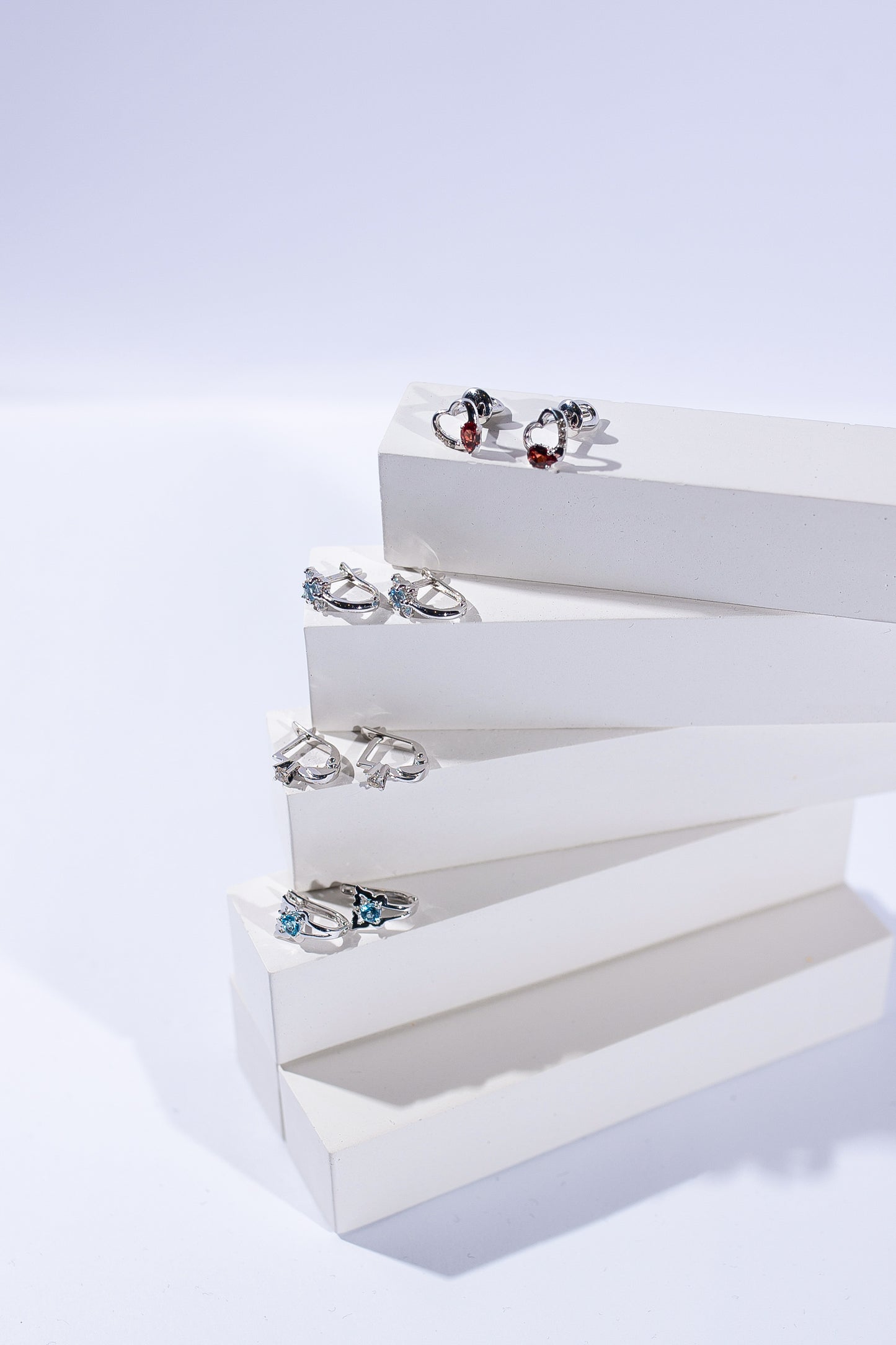 Чотири пари дитячих сережок з білого золота з діамантами зображені на підставках